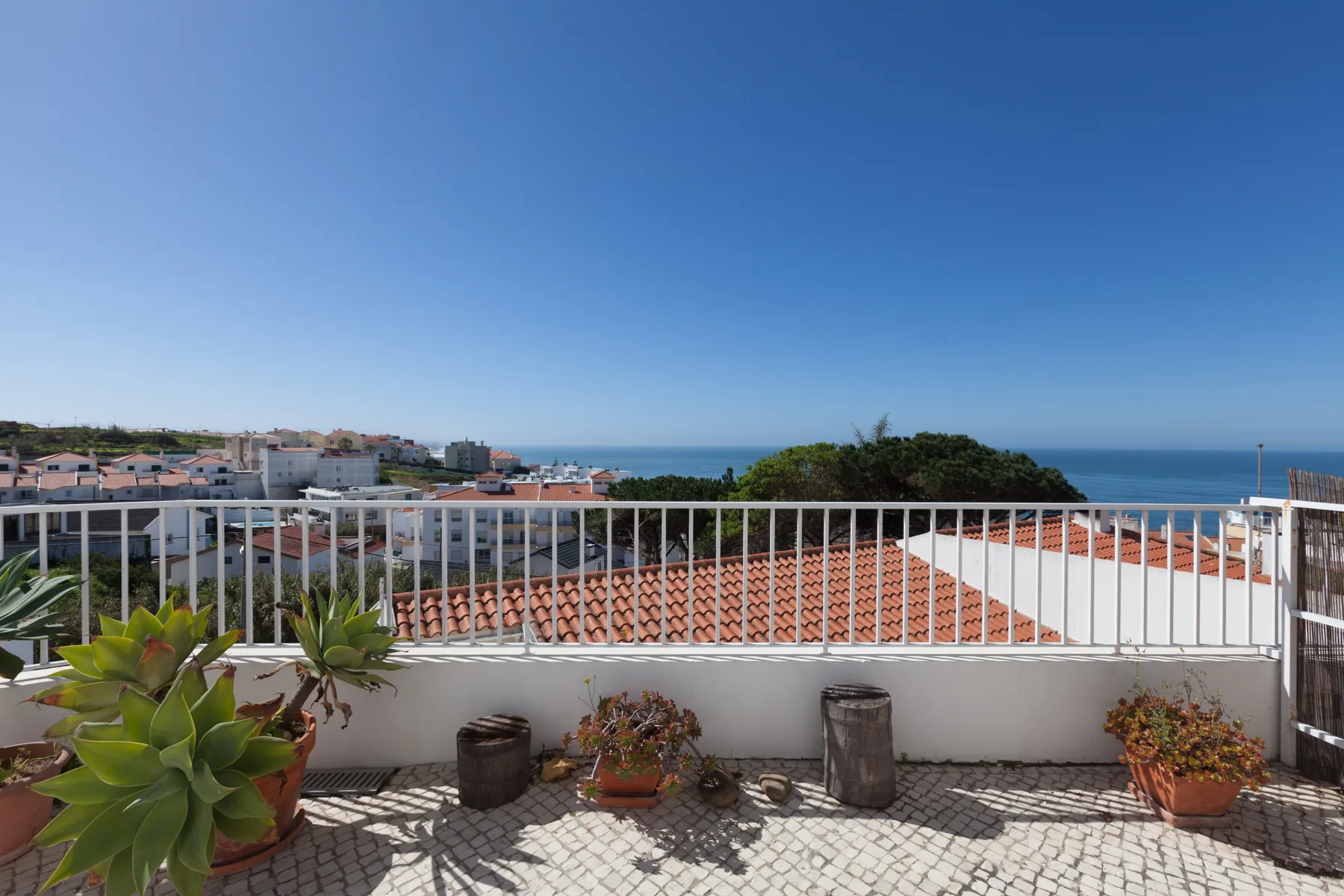 A rooftop terrace overlooks red-tiled roofs and the sea.