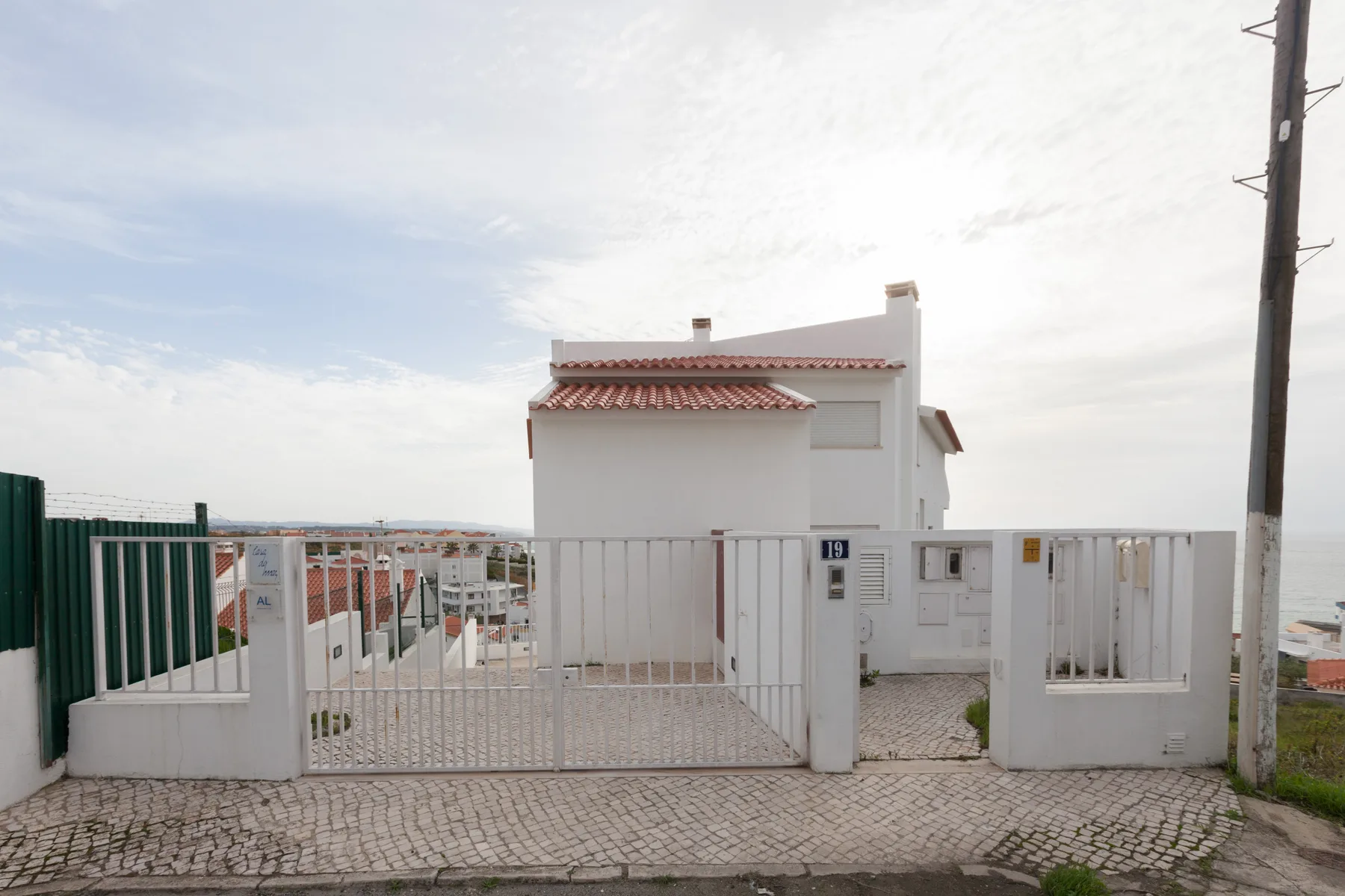 Un edificio blanco se encuentra detrás de una verja metálica y un muro bajo.
