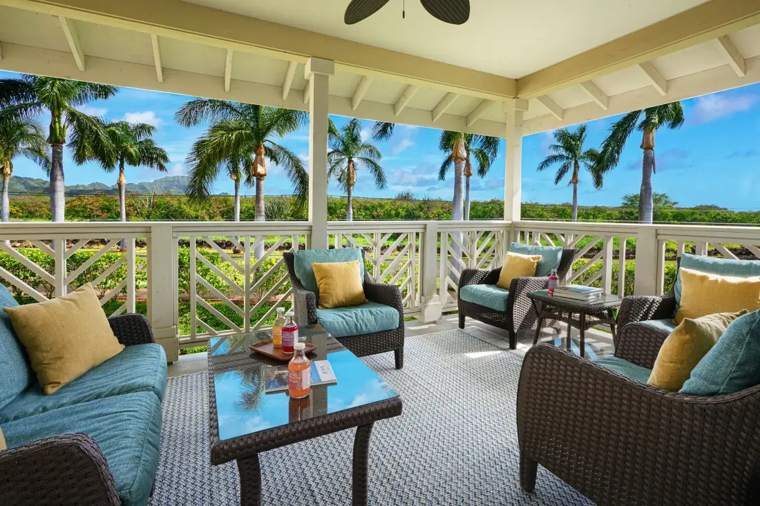 Una zona de estar exterior cubierta con muebles de mimbre y vistas a palmeras.