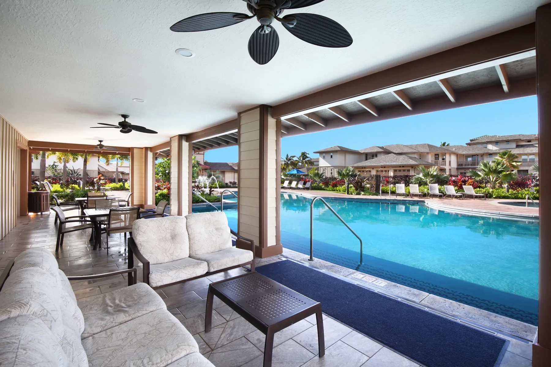 Un patio cubierto con asientos y una piscina al lado.