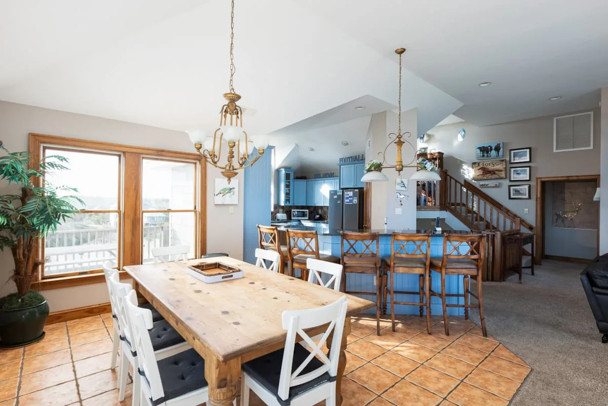 An open dining and kitchen area with a wooden table and blue island seating.