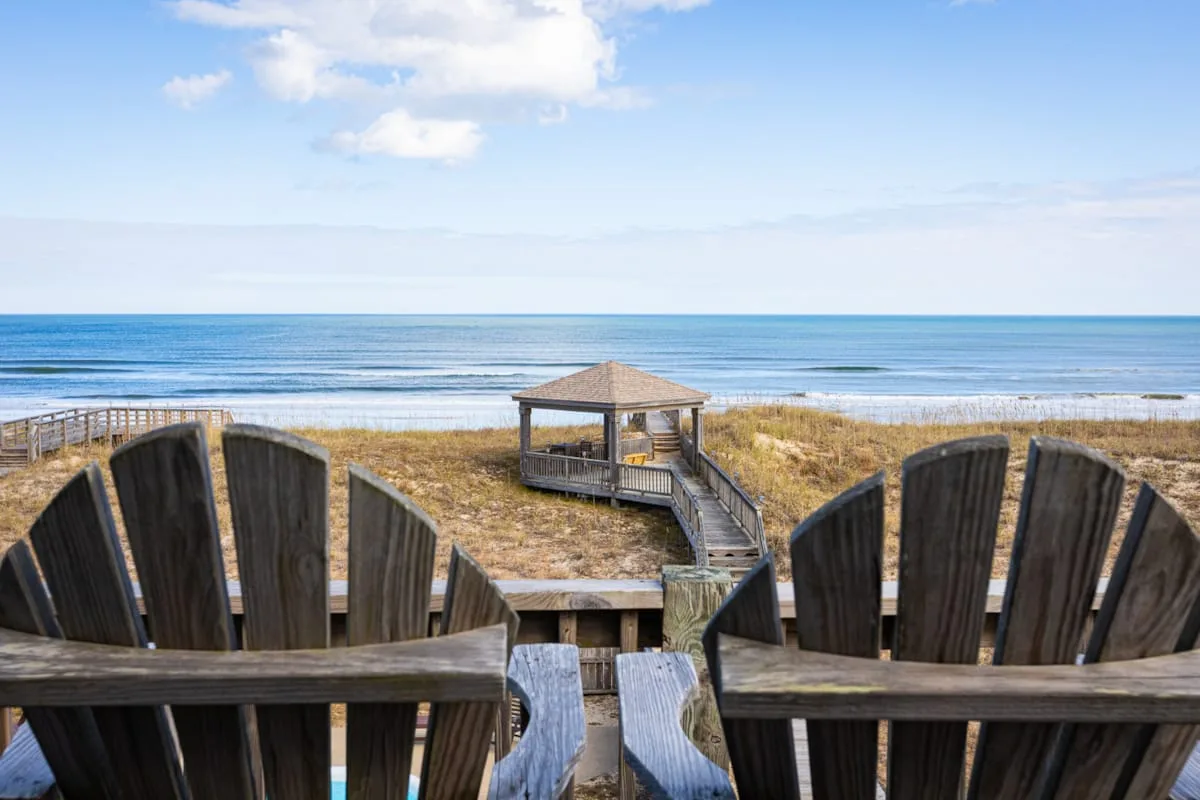 Wooden beach seating overlooks a boardwalk, gazebo, and ocean.
