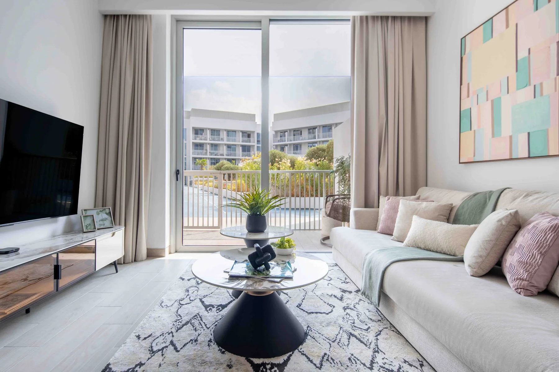 A bright living room with a sofa, coffee table, and sliding glass doors opening to a balcony.
