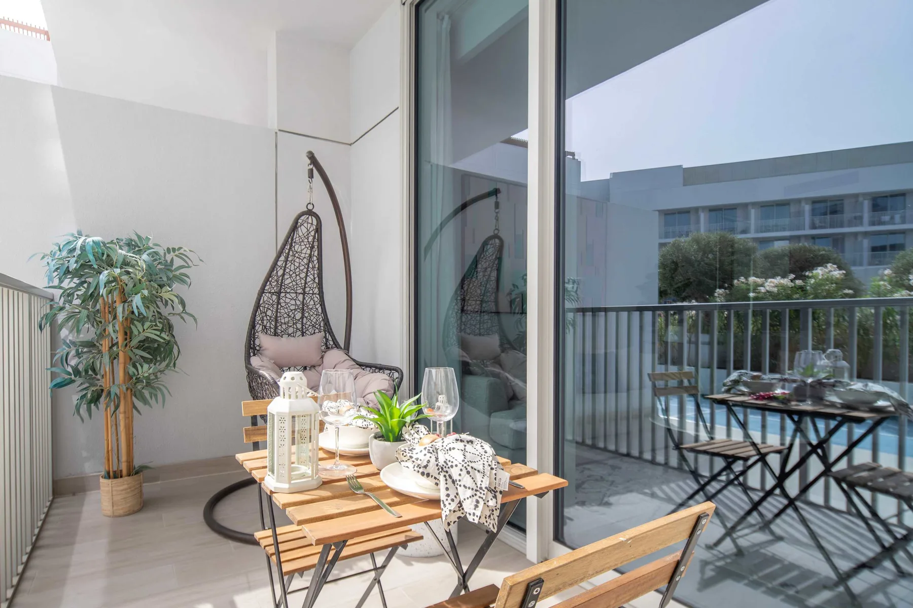 A balcony seating area with a hanging chair and a small table.