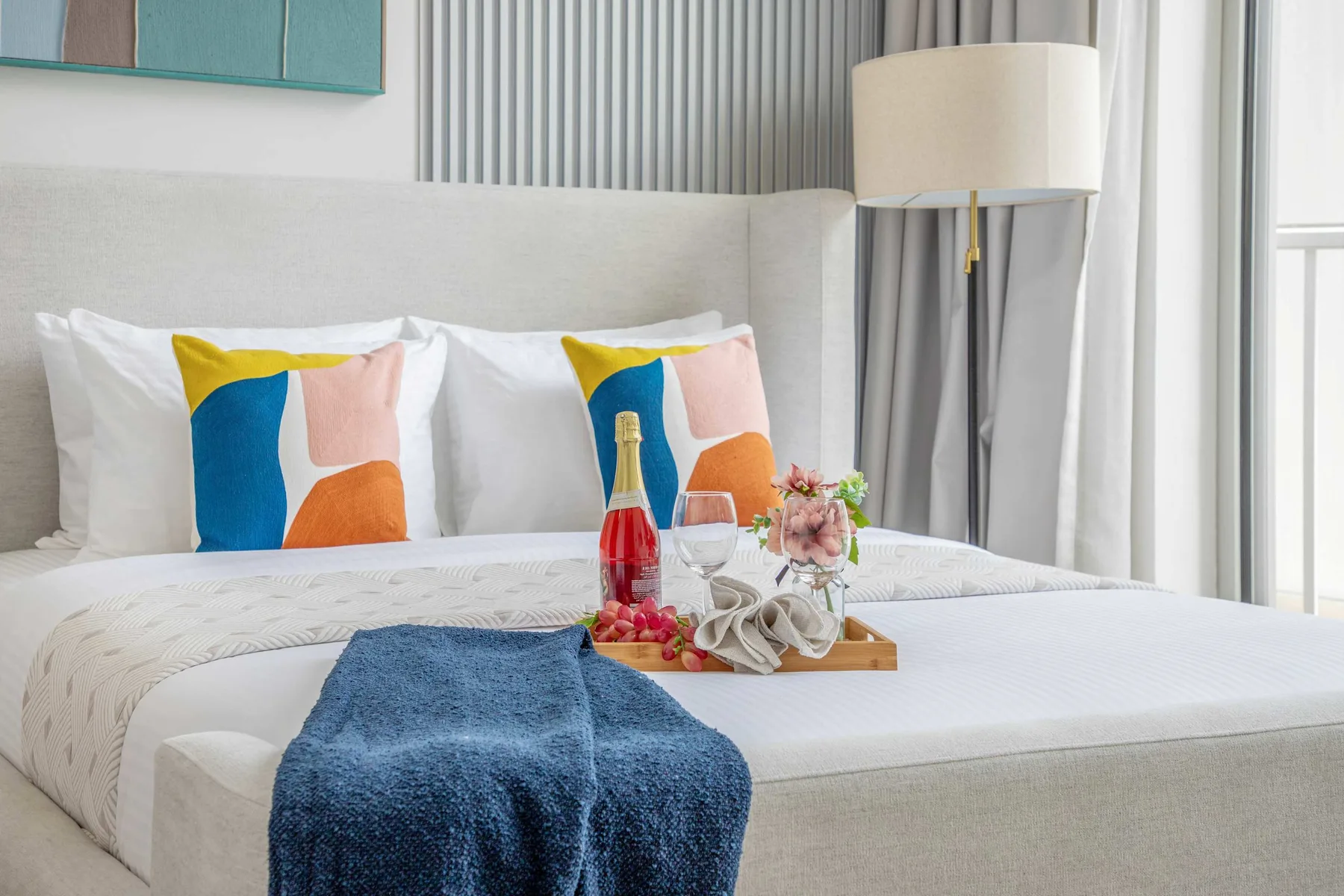 A neatly made bedroom with colorful pillows and a tray arranged on the bed.