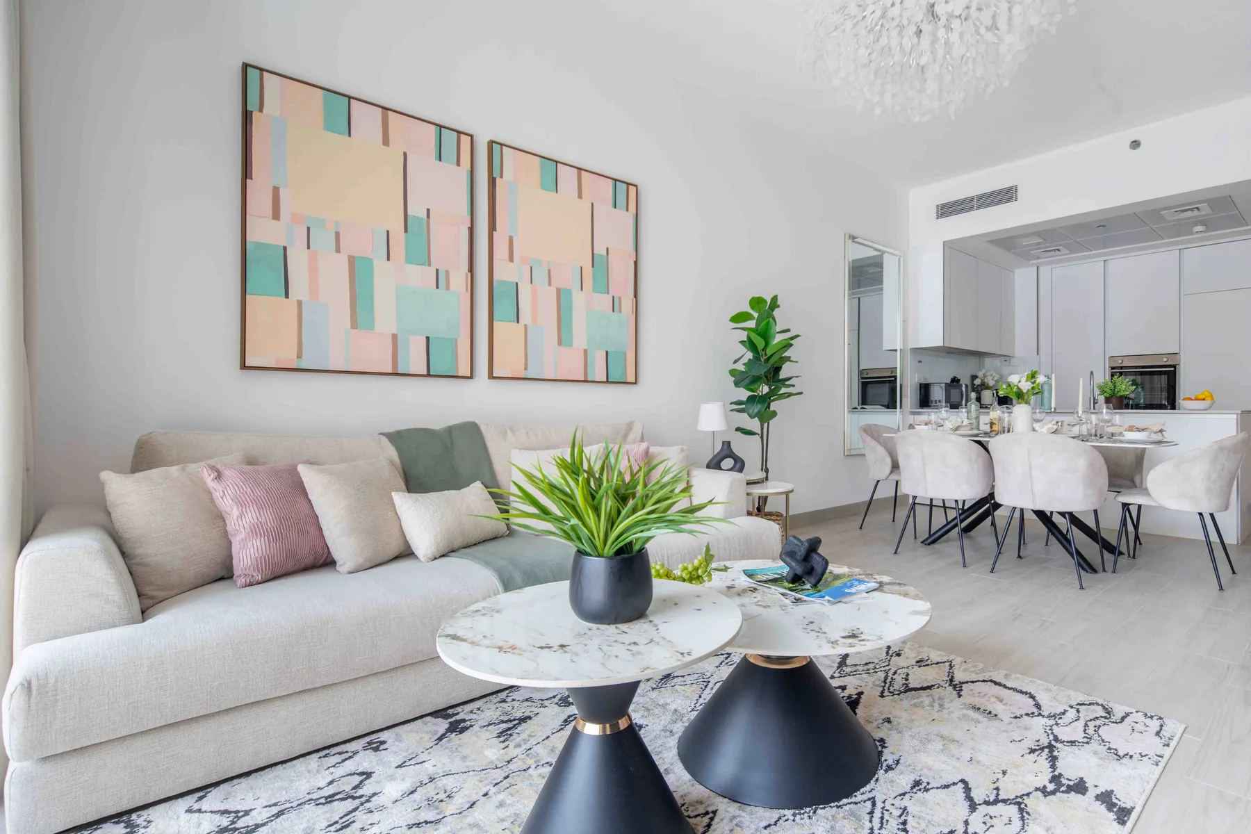 A bright living room with a sofa, coffee tables, and an open kitchen.