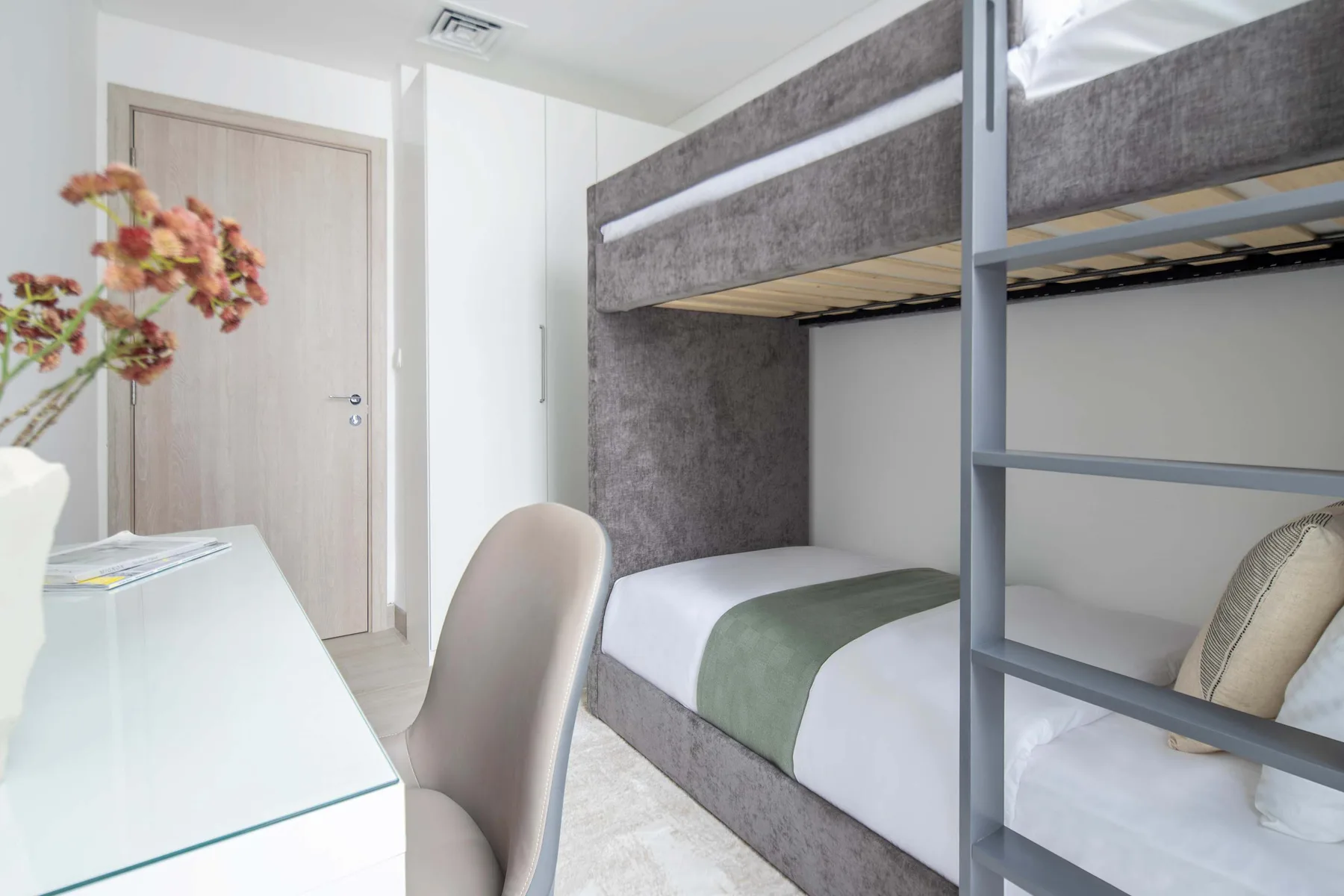 A bedroom with bunk beds, a desk, and a chair.
