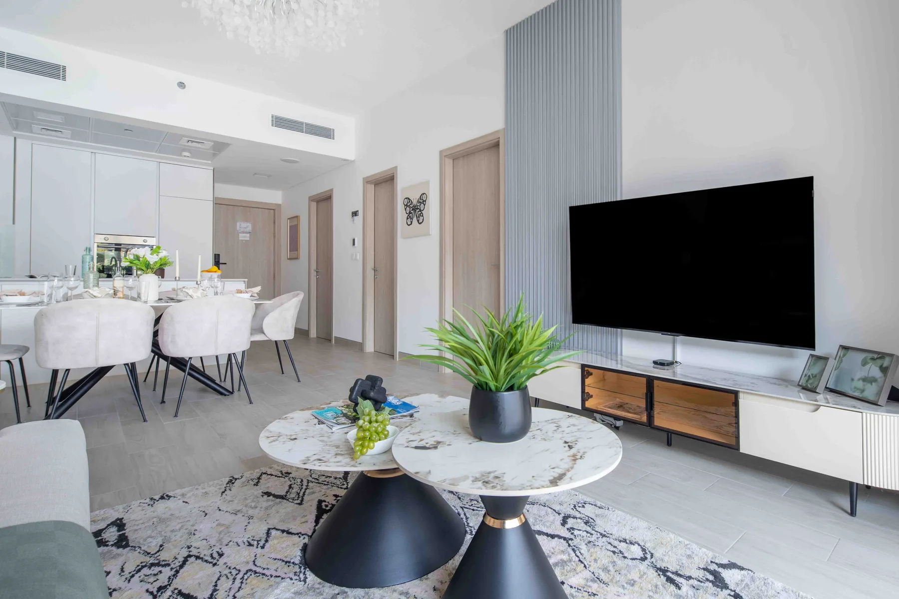A bright living and dining area with a television, dining table, and seating.
