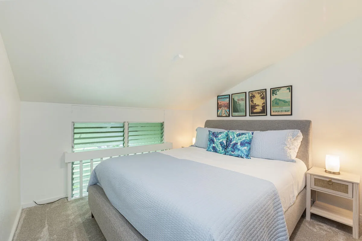 Un dormitorio con una cama, almohadas coloridas y cuadros sobre el cabecero.