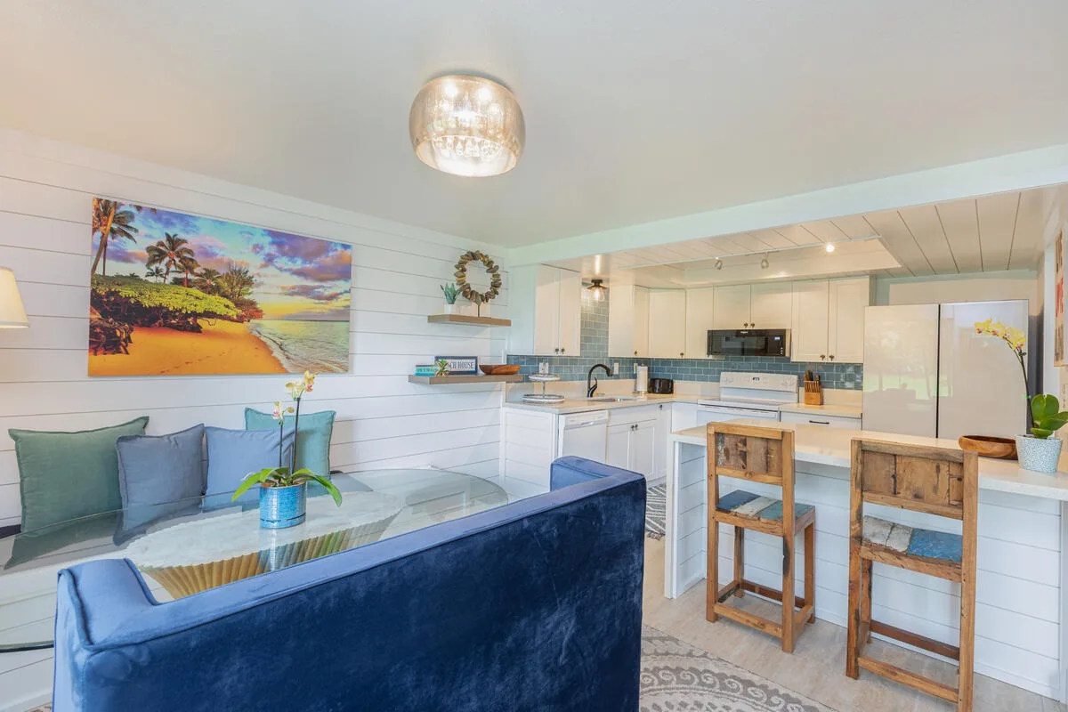 Una sala abierta y cocina con un sofá azul y una barra con taburetes.
