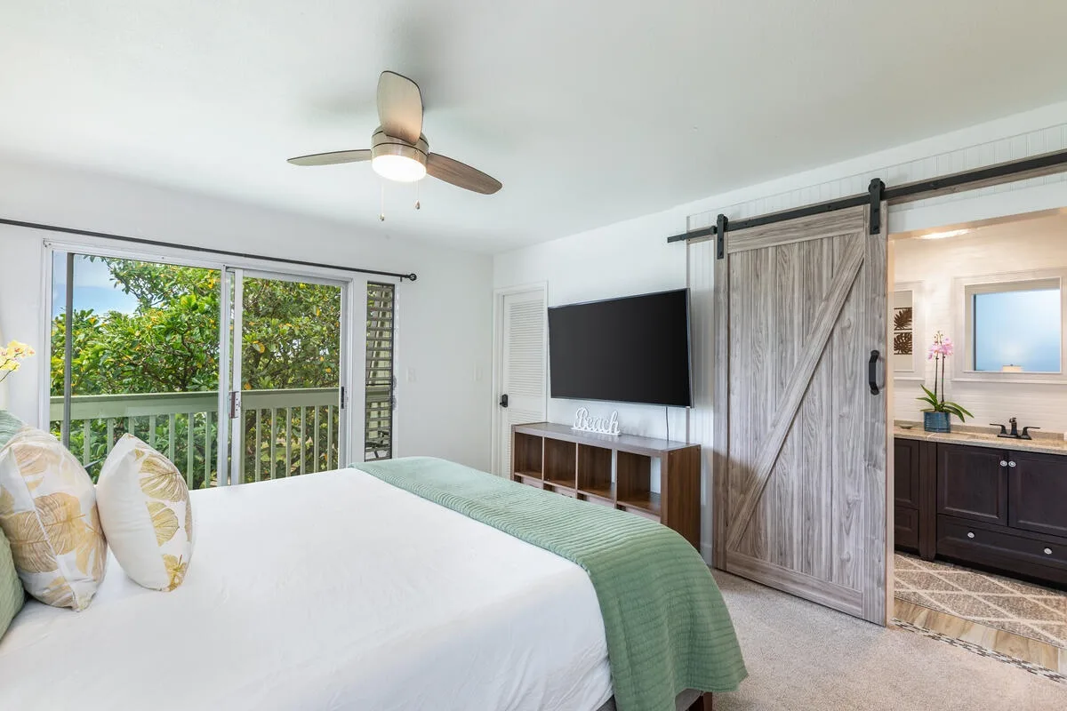 Un dormitorio con una cama grande, un televisor y una puerta corrediza de madera.