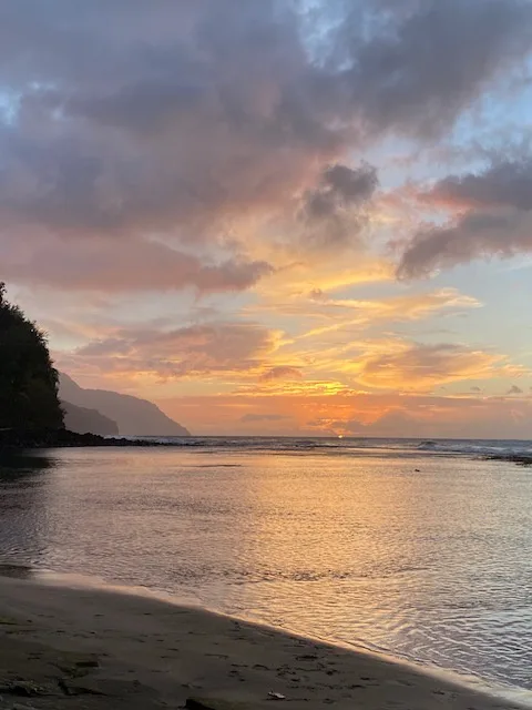Una playa al atardecer, con luz dorada reflejada en el agua.
