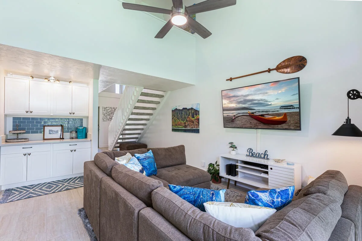 Una sala de estar con asientos seccionales y un mueble para televisión.