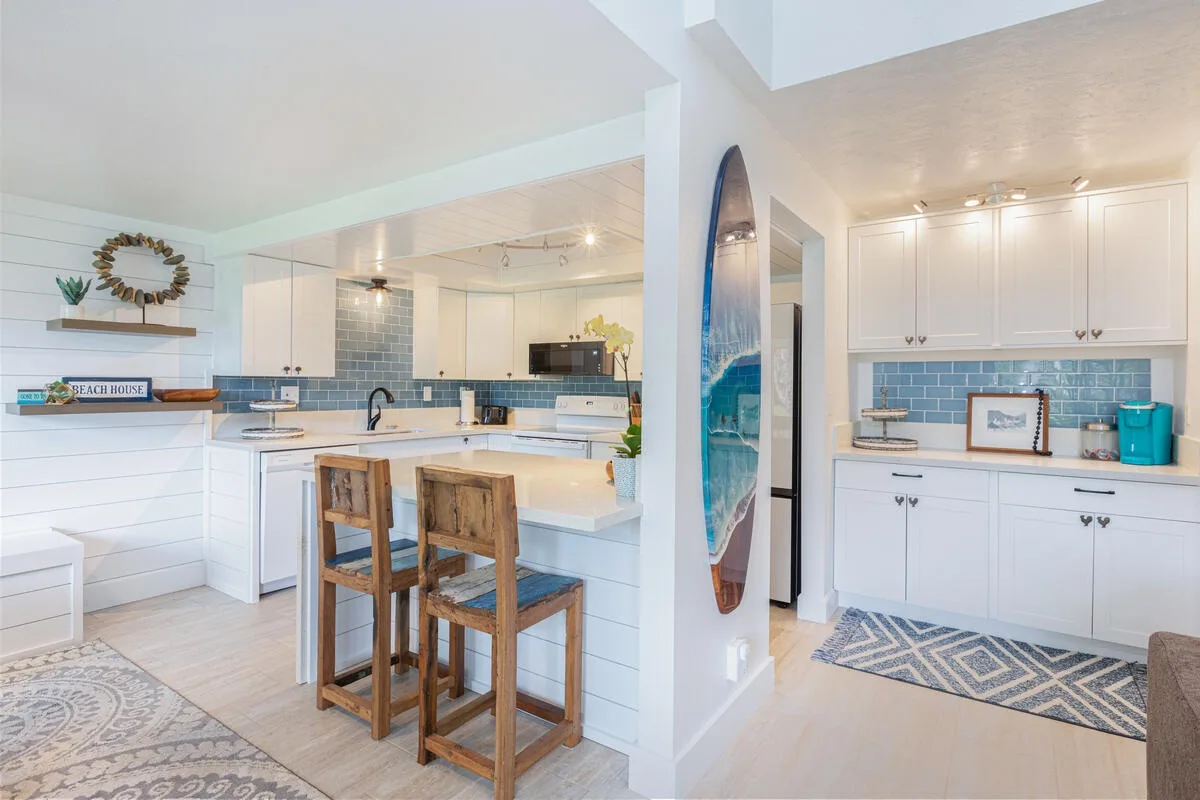 Una cocina luminosa con una isla central y un salpicadero de azulejos azules.