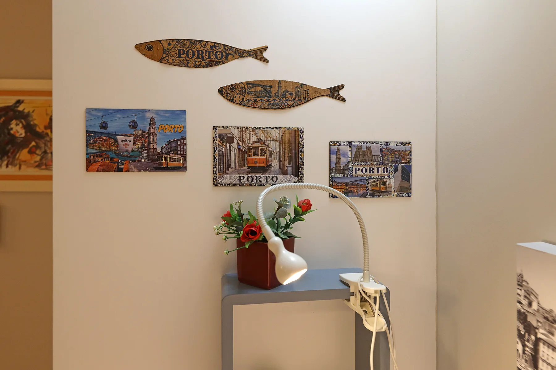 Interior wall display with Porto-themed artwork above a small table and flowers.
