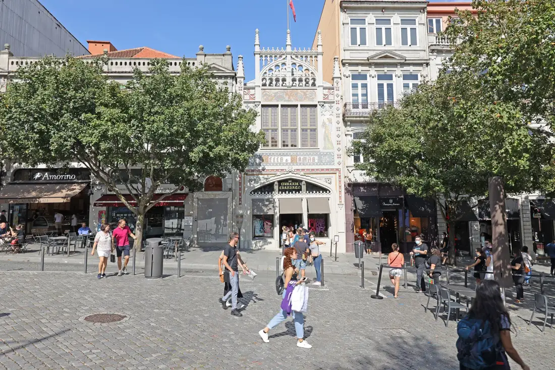 A busy pedestrian square with historic buildings, shops, and outdoor seating.