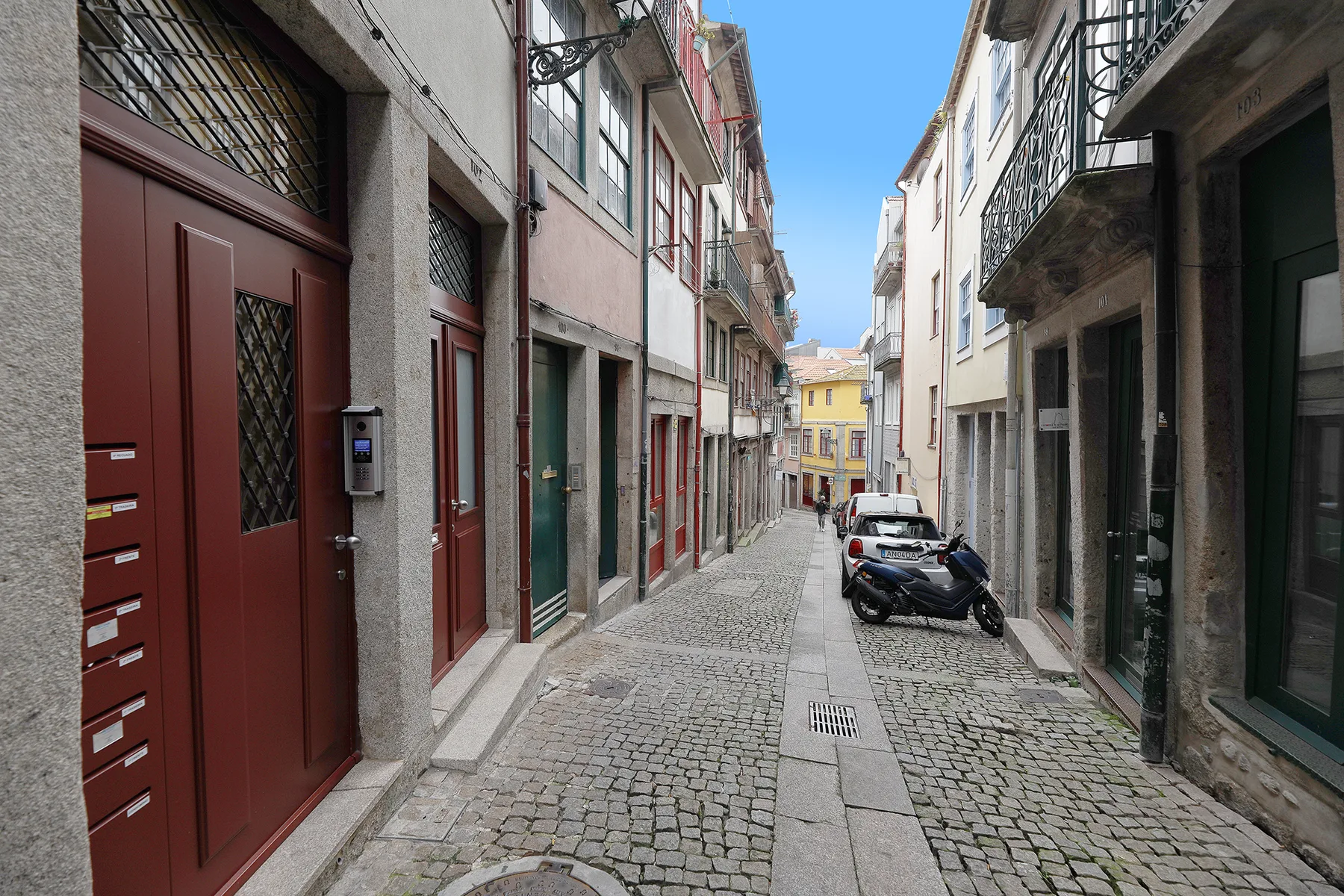A narrow cobblestone street runs between closely spaced buildings.