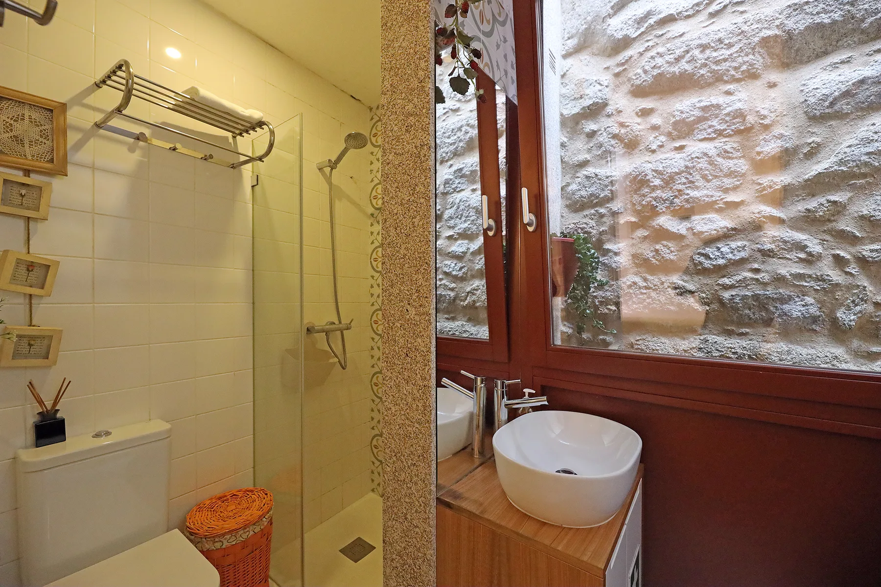 A bathroom with a glass shower and a vessel sink beside a window.