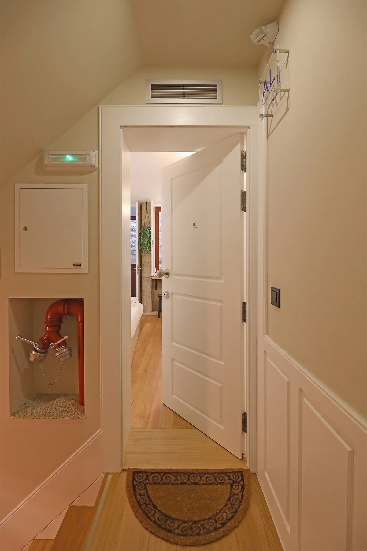 A narrow entry hall with an open door leading into a brighter room.