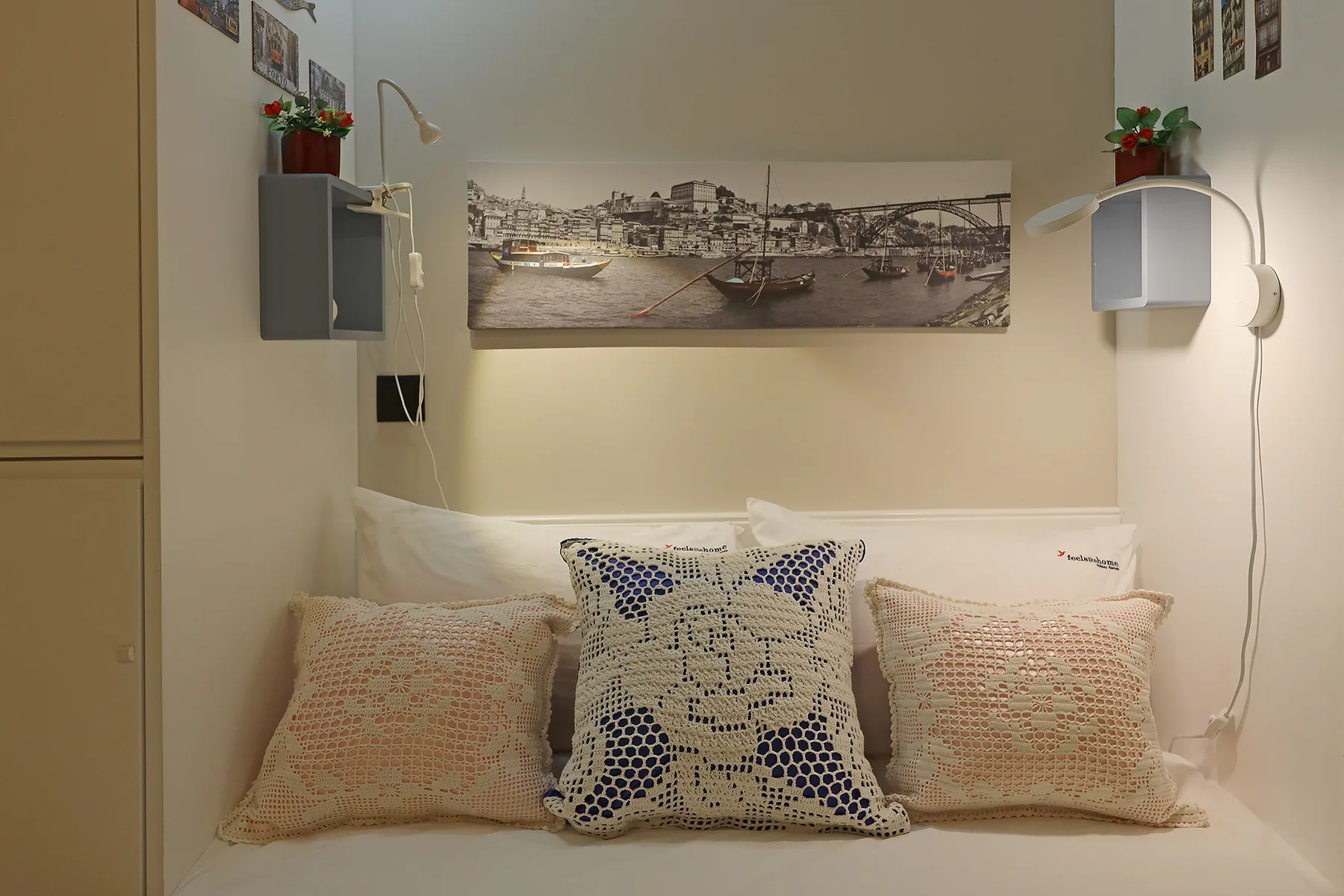 A bed with decorative pillows sits beneath a panoramic wall picture.