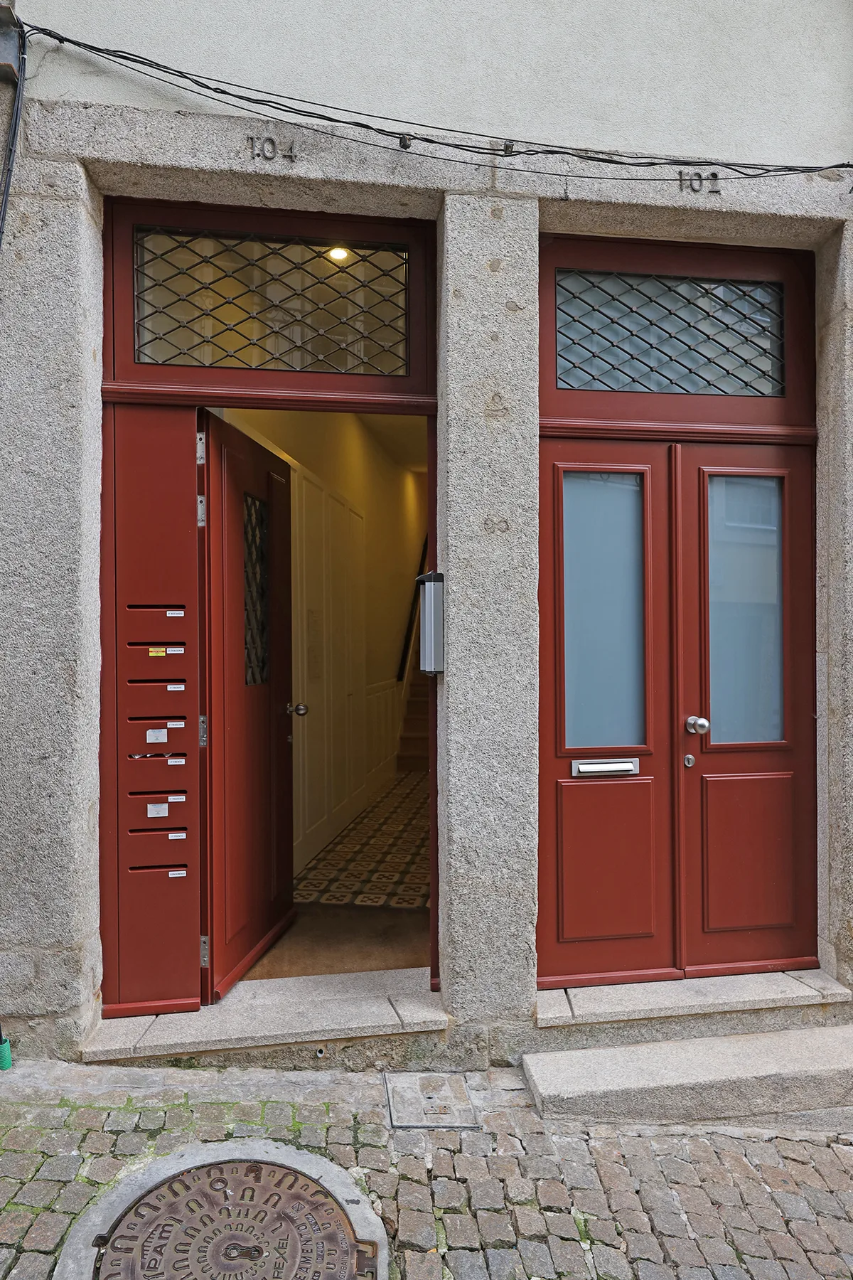 A stone building facade with red doors opens onto a narrow entrance.