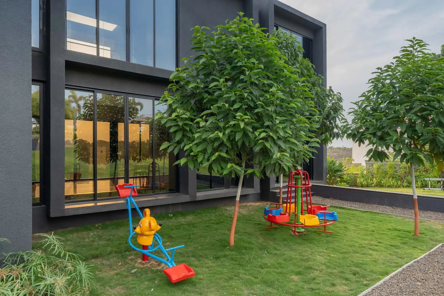 Una zona de juegos al aire libre con césped y juegos coloridos junto a un edificio moderno.