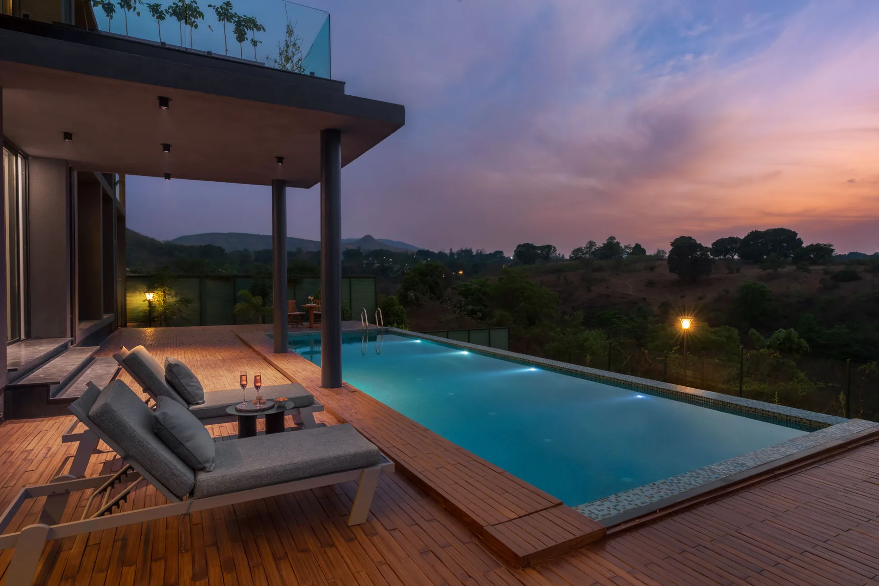 Una piscina y asientos al aire libre dan a una colina al anochecer.