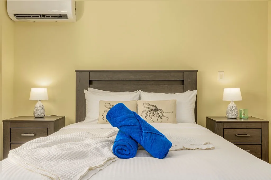 Sink into plush pillows and fresh linens in your sun-kissed bedroom, where climate-controlled comfort and soft bedside lighting invite restful nights and lazy mornings.