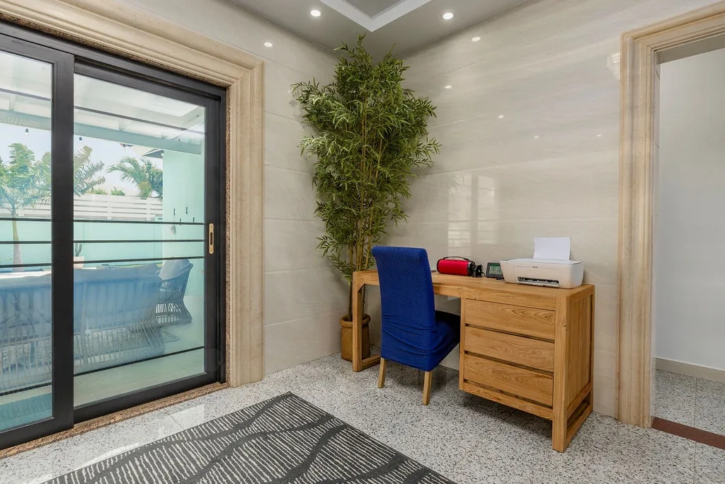 Your private workspace awaits, bathed in natural light from the balcony door and framed by lush greenery. Settle in at the wooden desk, where everything you need is within reach—perfect for catching up on work or planning your next adventure.