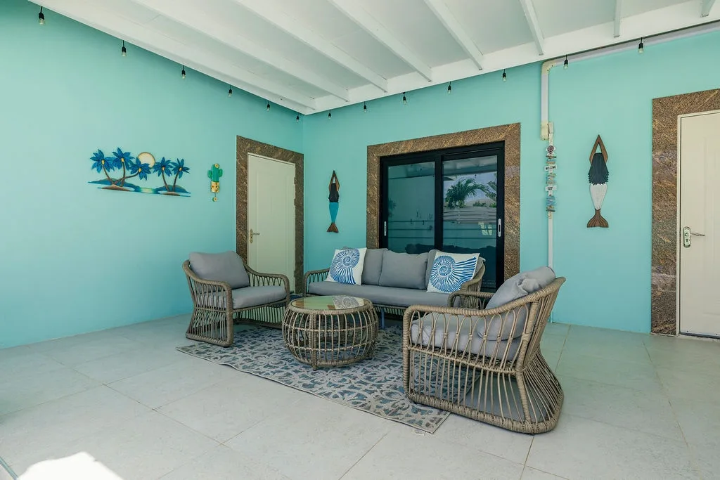 Step into your breezy coastal escape with cheerful turquoise walls, woven rattan seating, and playful beach-themed accents that set the perfect vacation tone.