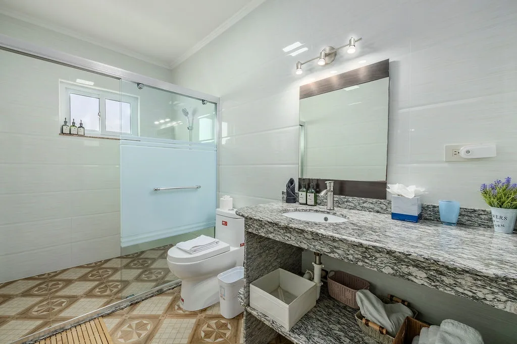 Step into your private spa-like retreat with a spacious walk-in shower, elegant granite countertop, and abundant natural light. Everything is thoughtfully arranged so you can refresh and unwind in style.