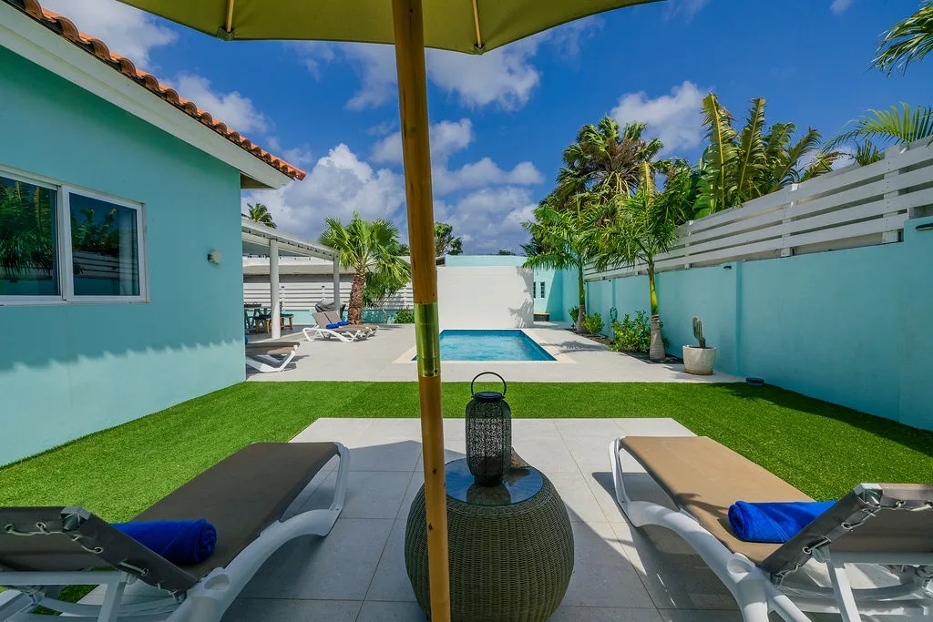 Stretch out on your private lounge chairs beneath a shaded umbrella, soak in the sparkling pool, or stroll across lush lawn framed by swaying palms and bright blue skies—your own tropical escape awaits.