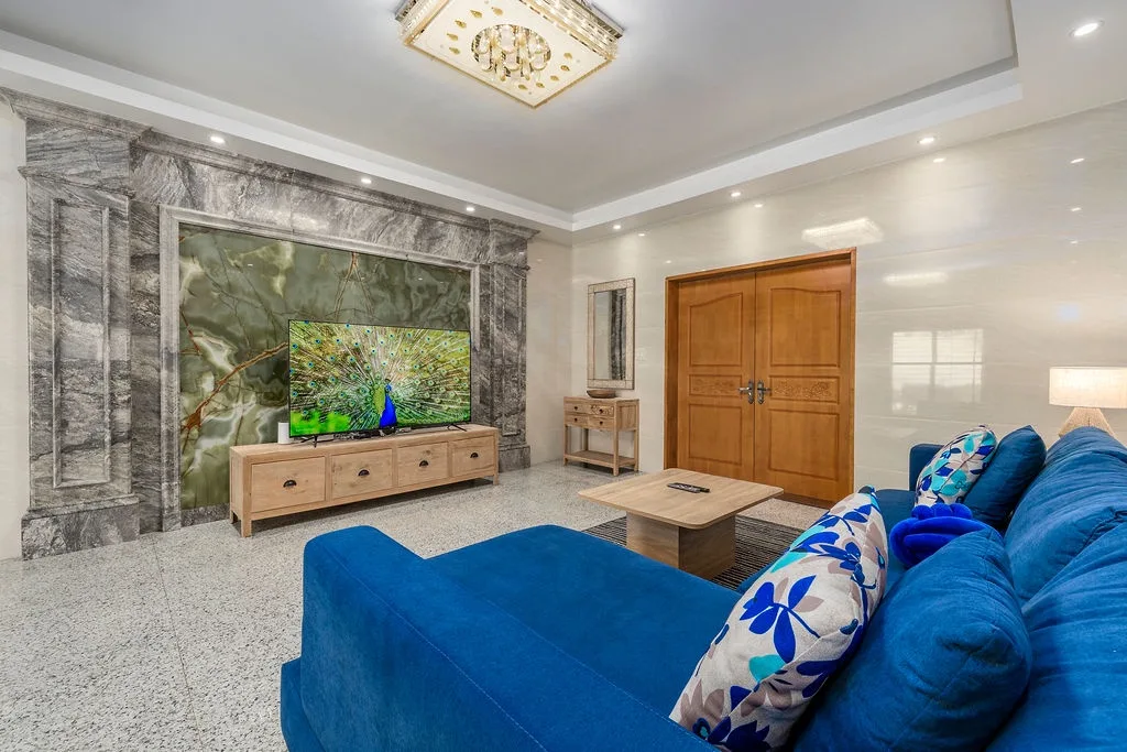 Settle into vibrant blue couches and enjoy your favorite shows on the large screen TV in this stylish, light-filled living space with beautiful artistic accents.