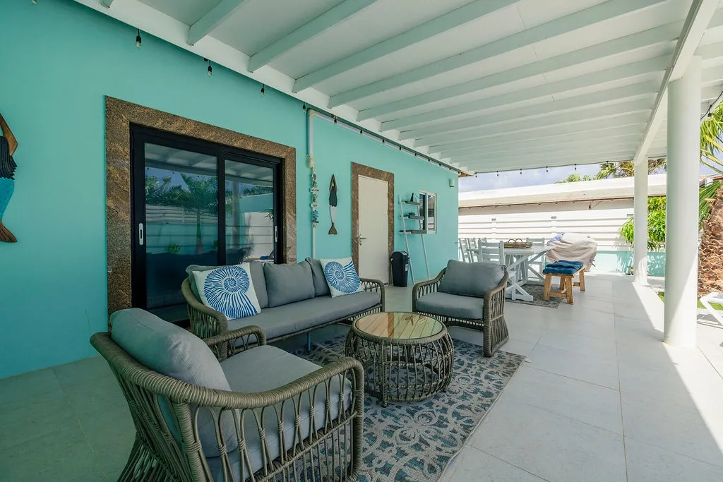 Sink into plush seating on your covered patio, where cool turquoise walls and breezy island vibes set the tone for effortless relaxation.