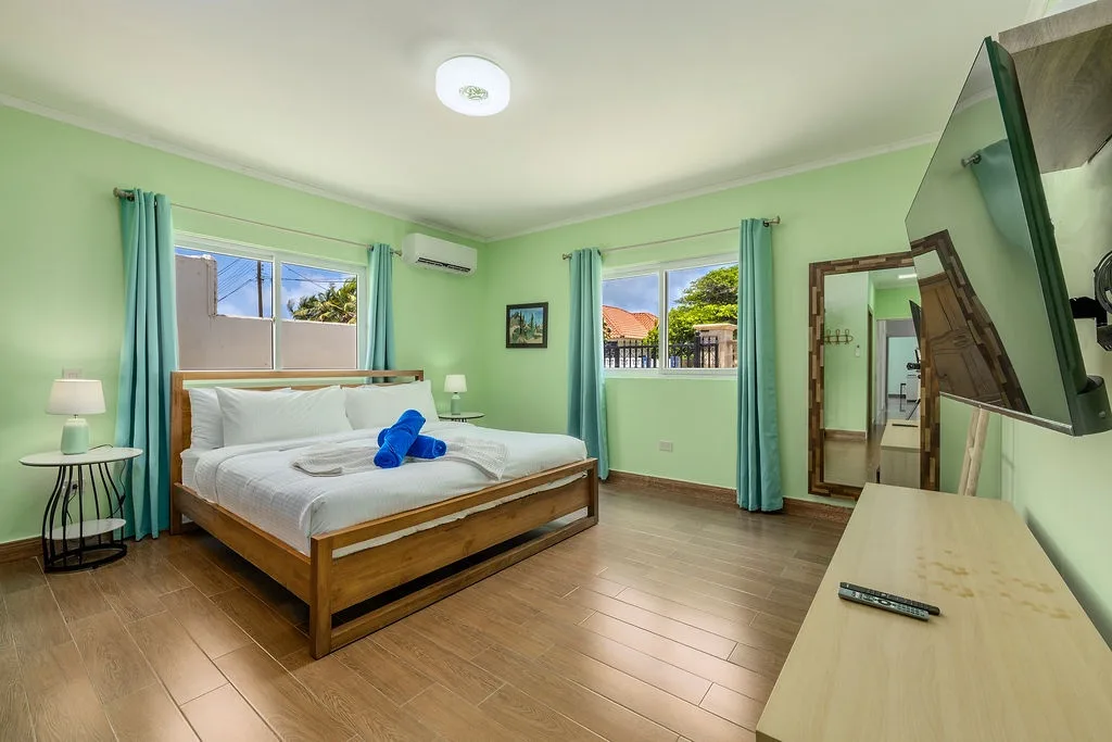 Your bright bedroom features a comfortable bed with crisp linens, calming mint walls, and natural light from dual windows. Unwind with entertainment on your flat-screen TV or step into your private ensuite bathroom.