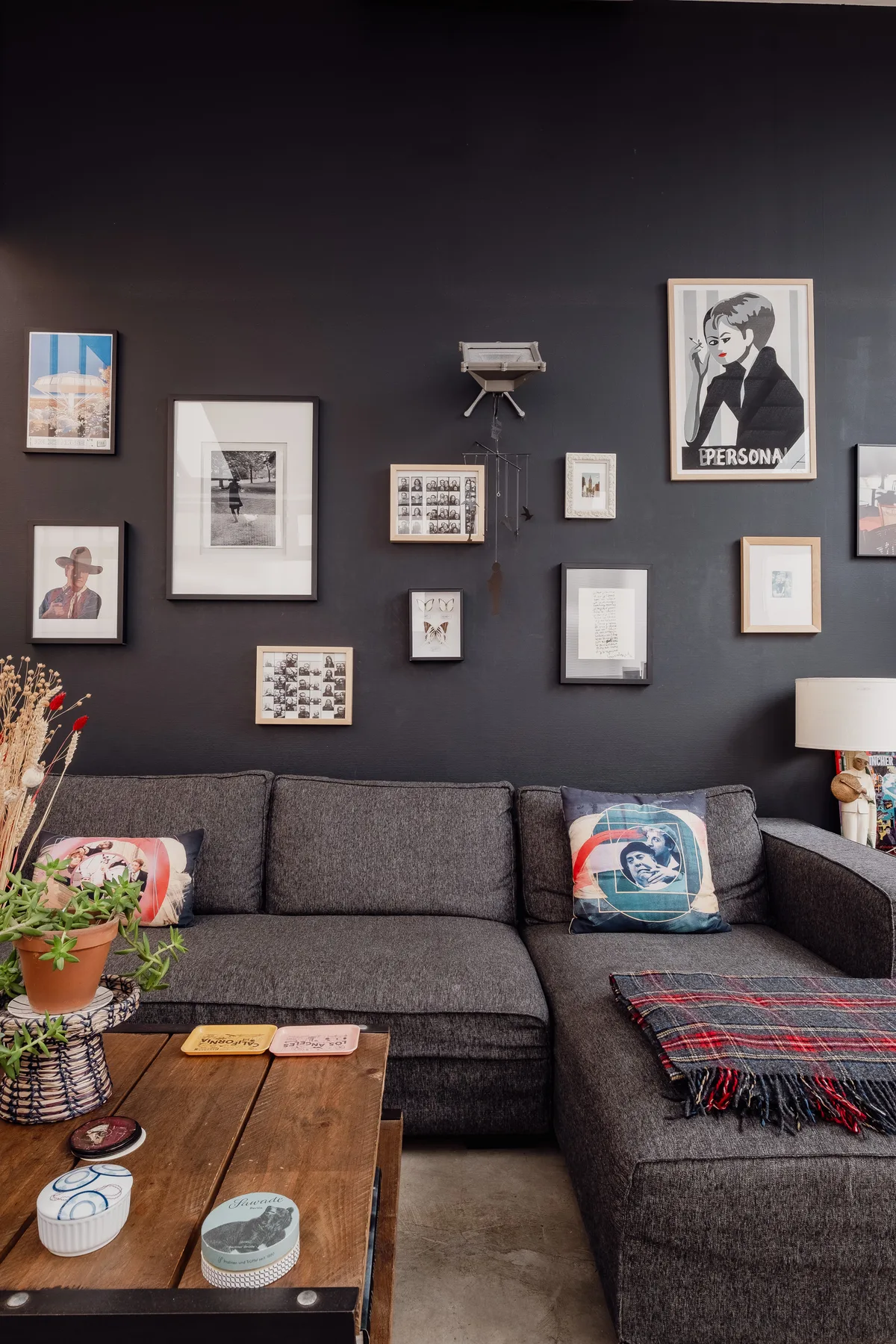 A living room with a dark sectional sofa and framed artwork on the wall.