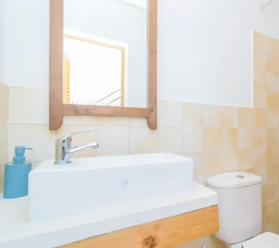 A bathroom vanity with a sink and mirror beside a toilet.