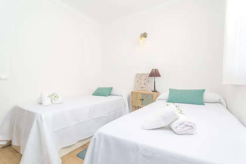 A bright bedroom with two beds dressed in white linens.