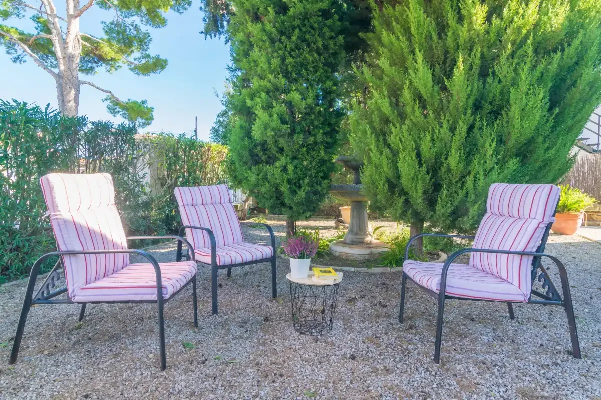 Outdoor seating area with striped cushions arranged around a small table in a leafy garden.