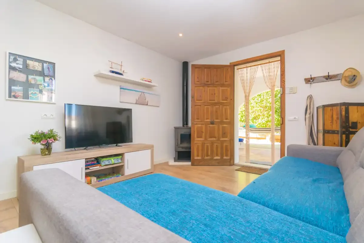 Living room with seating, a television, and an open doorway to the patio.