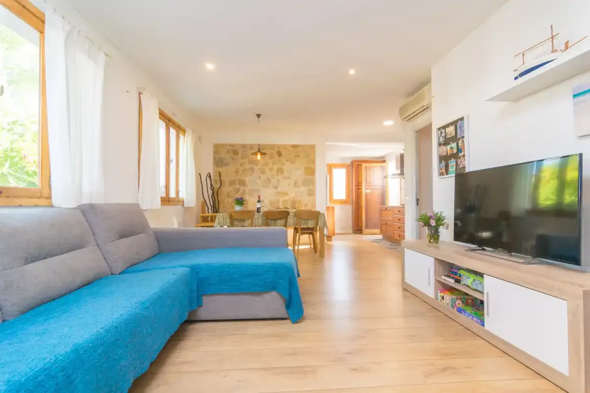 A bright living room with a blue sectional sofa and television.