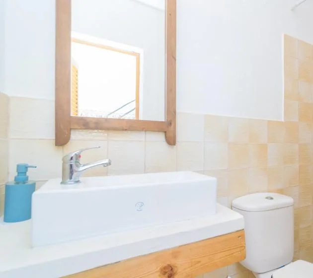 A bathroom vanity with a sink, mirror, and toilet.