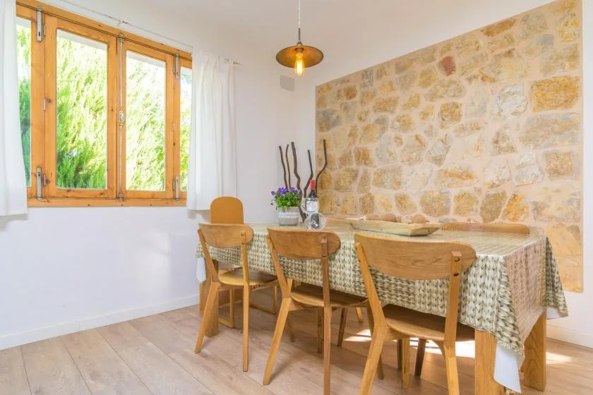 A dining area with a table and wooden seating beside a large window.