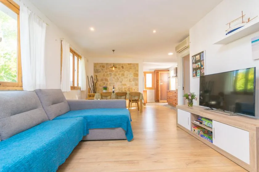 A bright living room with a blue sectional sofa and television.