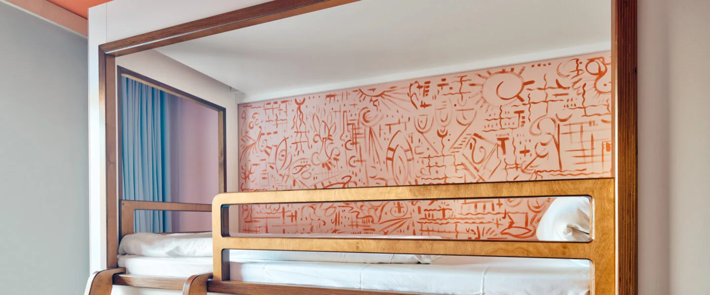 A built-in-looking bunk bed with a wooden frame and painted designs on the back wall.