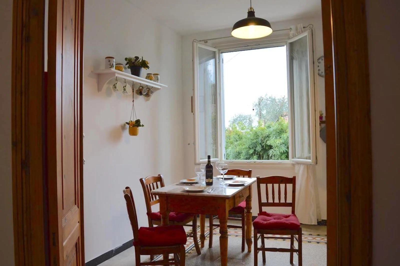 A dining area with a wooden table and chairs beside an open window.