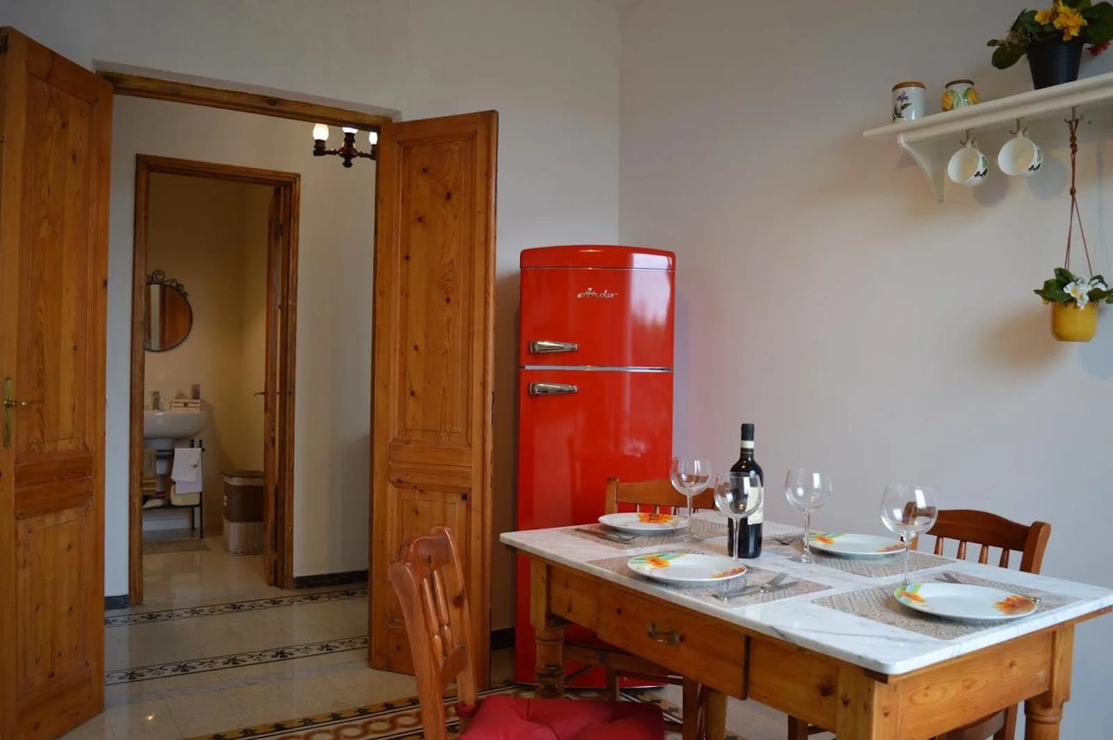 A dining area with a wooden table and a bright red refrigerator.