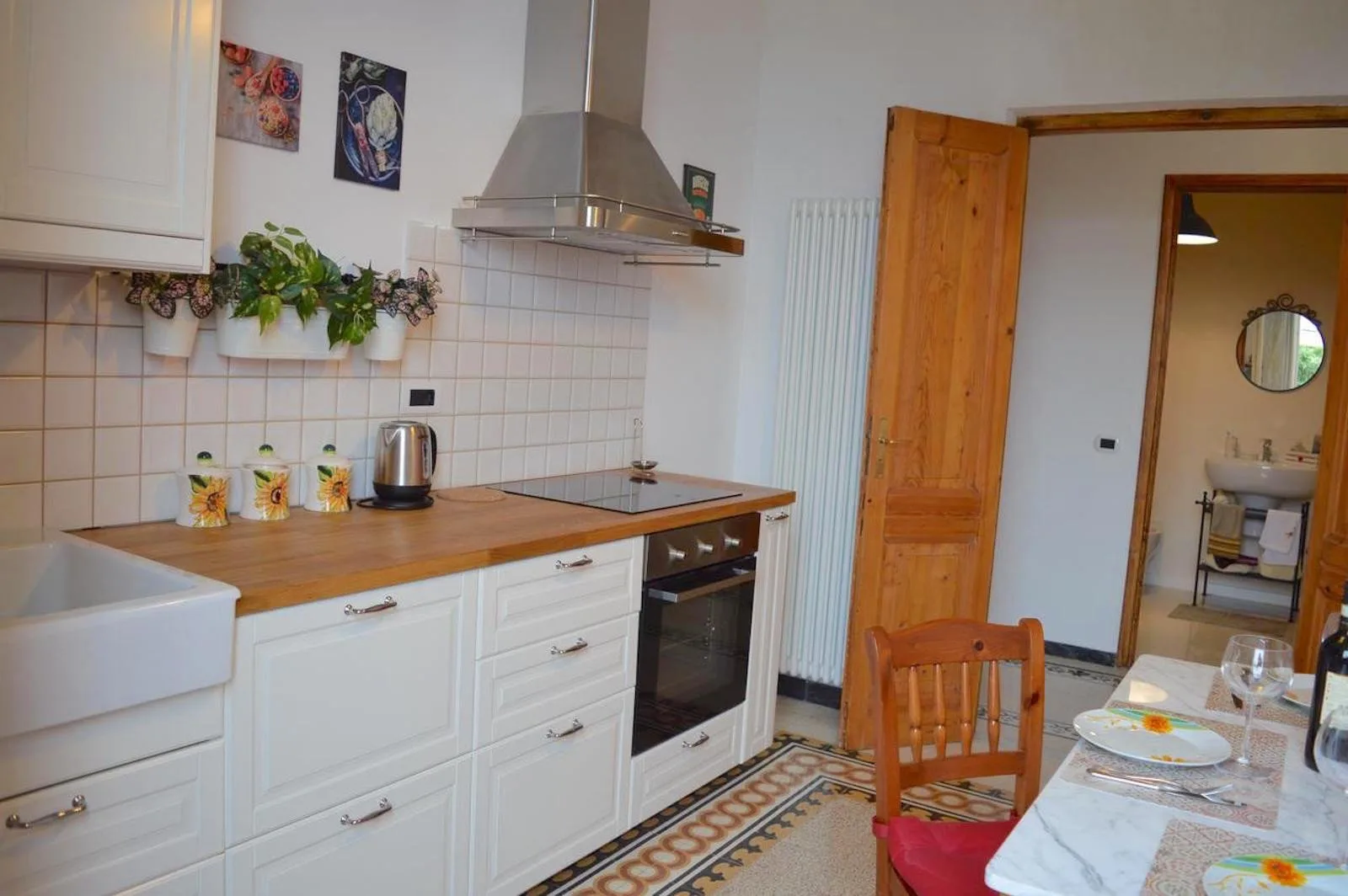 A bright kitchen with white cabinets, a wooden countertop, and a dining table.