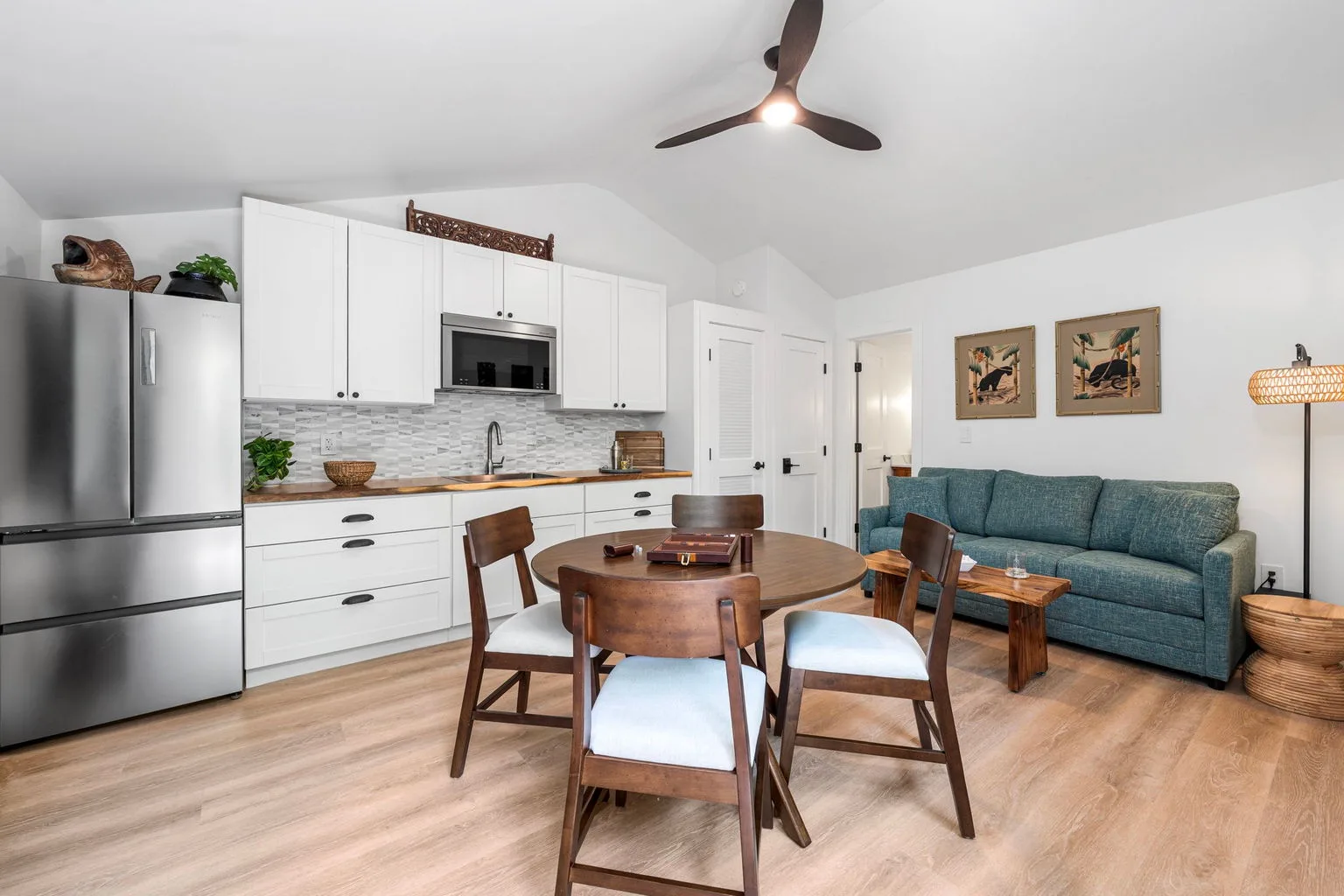 An open kitchen and dining area with a round wooden table and blue seating.