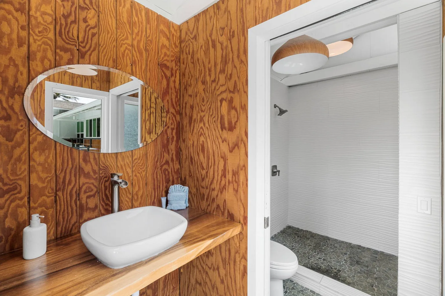 A bathroom vanity with a white vessel sink sits beside an open shower area.